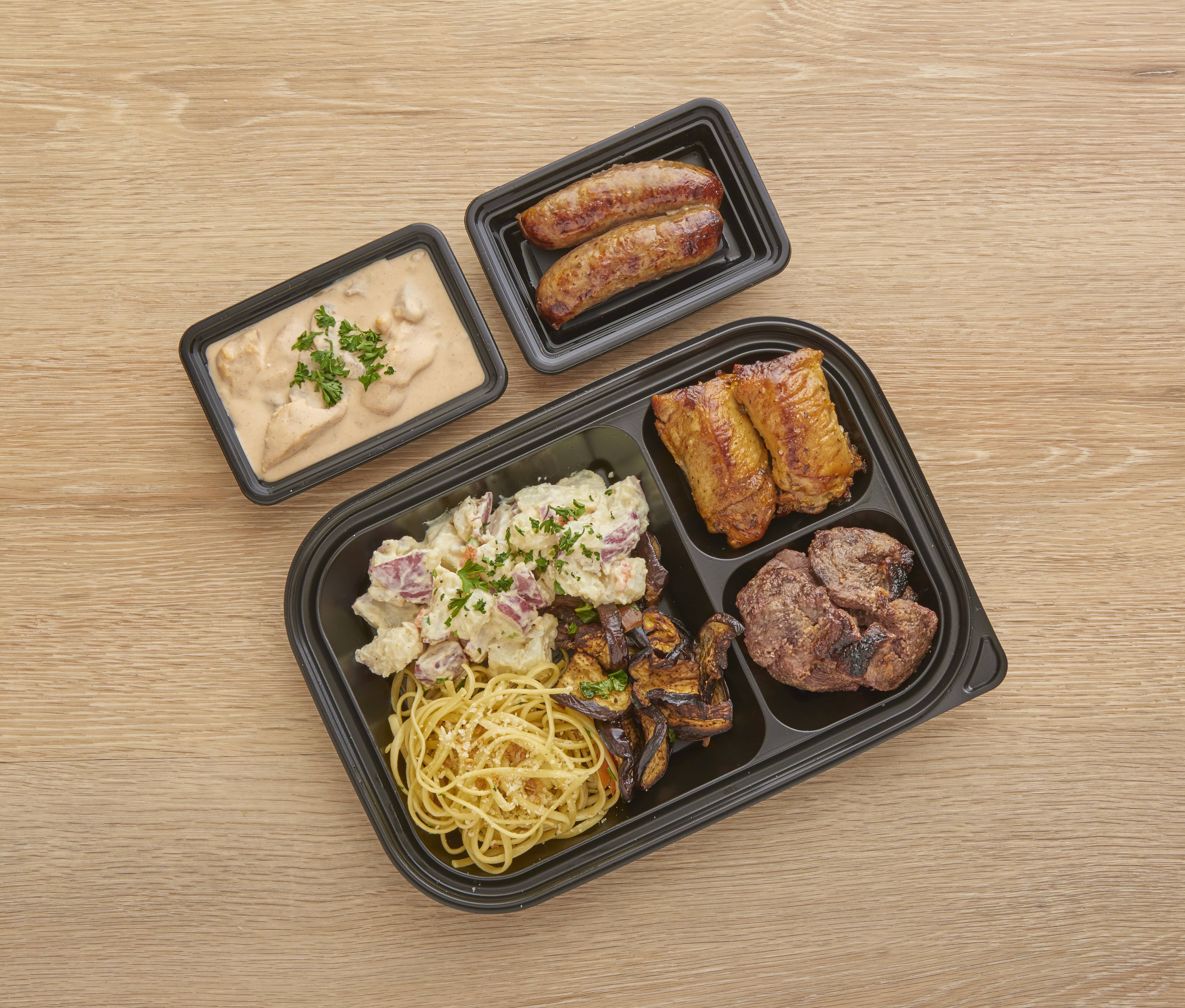 A plate of noodles, sausage, potato salad and meats
